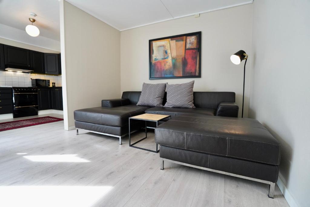 波什格伦Sentralt i rolig bygård, med heis, egen, veranda & 85" Smart TV的客厅配有沙发和桌子