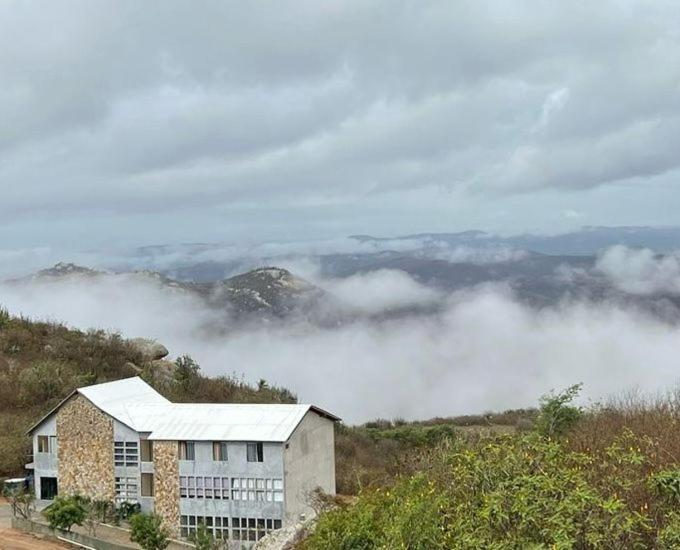 Serra de São BentoPOUSADA MIRANTE DO VALE的云层在山边的建筑物