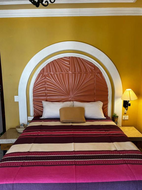 阿瓜斯卡连特斯Hotel La Casa de María Joyita的一张大床,在房间内配有大型木制床头板