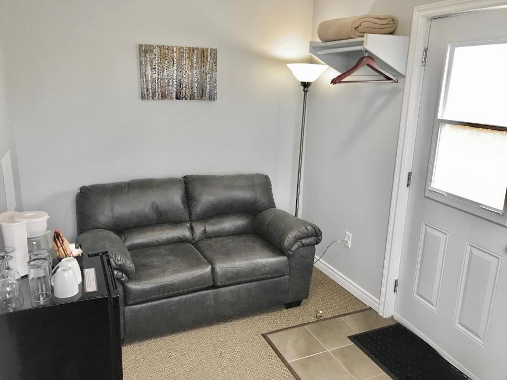 洛基港Stay in Gros Morne的一张黑色皮沙发,位于一个有门的房间