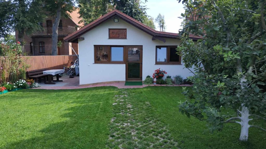 鲁恰内尼达Domek z kominkiem, Ukta 63, Mazury,的一座带草地庭院的白色小房子