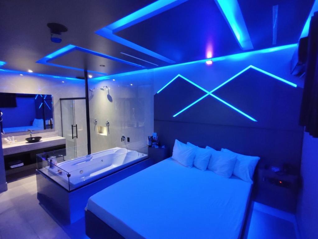 索罗卡巴Prestige Motel 2的一间带浴缸的卧室和一间带蓝色灯光的浴室