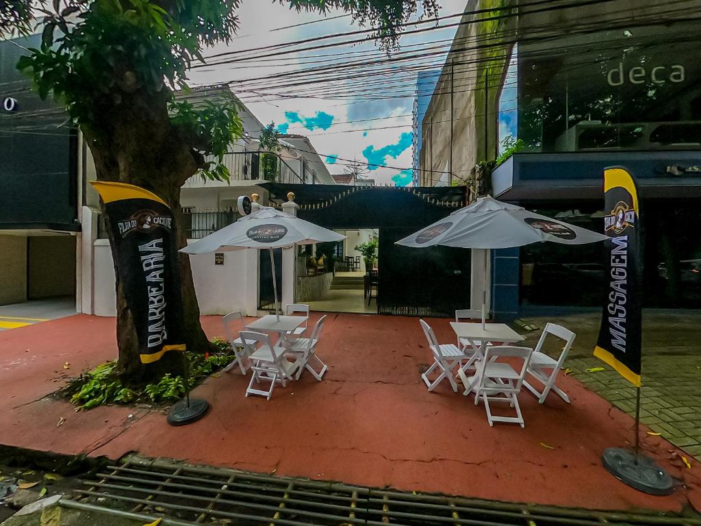 贝伦Hotel Filha do Cacique的树旁的一组椅子和遮阳伞