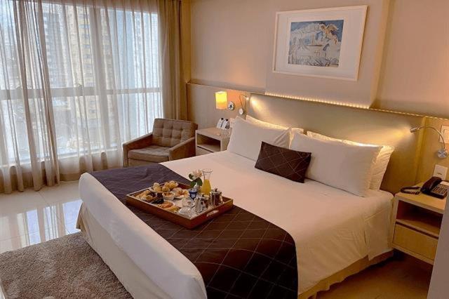 巴西利亚Cullinan Hplus Premium Flat Vip的一间酒店客房,配有一张床铺,上面放着一个食物托盘