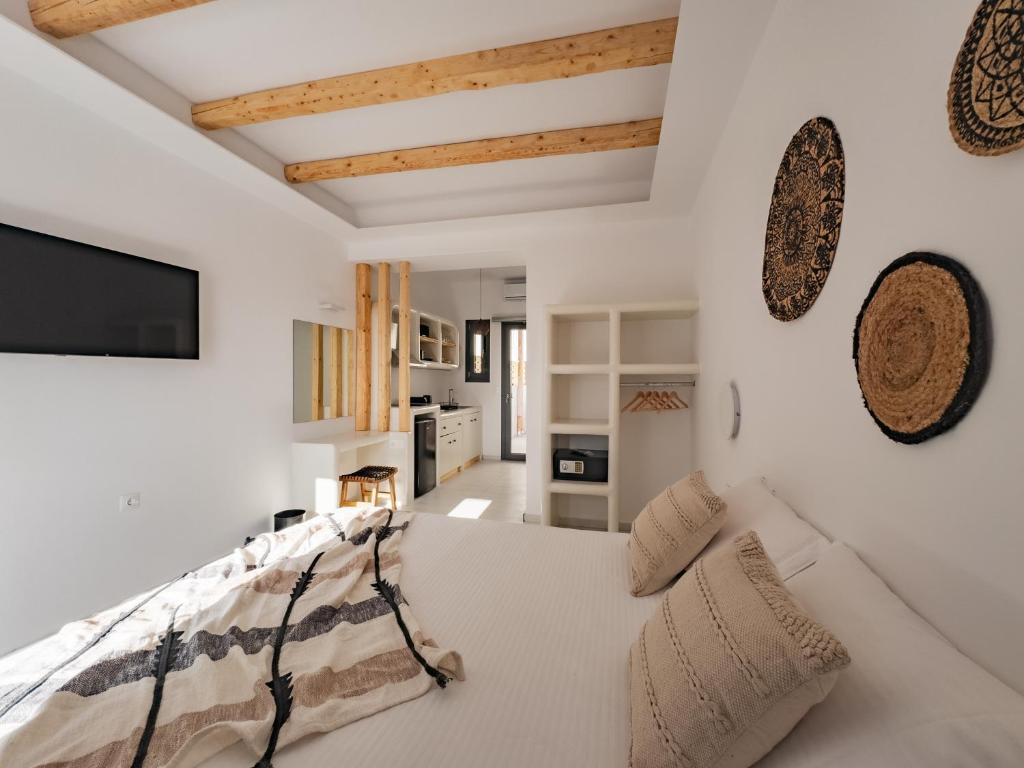 纳乌萨Alonia Suites的卧室拥有白色的墙壁,配有带枕头的床铺。