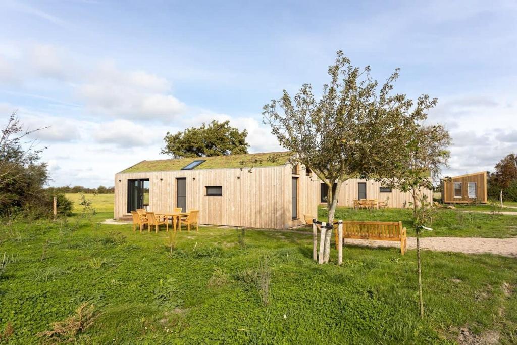 韦斯特卡佩勒Hello Zeeland - Zeeuwse Liefde Tiny House 8的田野里带桌子和树的棚子