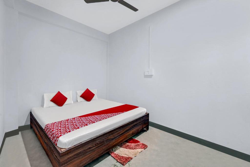 巴特那OYO Flagship YUVRAJ Hotel的白色客房内的一张带红色枕头的床