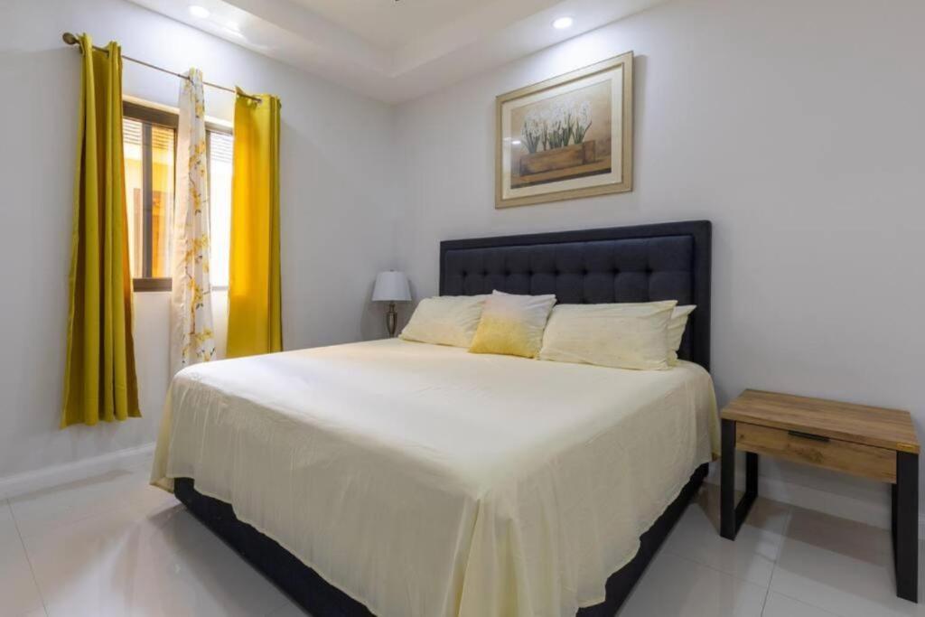 Old HarbourLuxury Palm的卧室配有一张白色大床和黄色窗帘