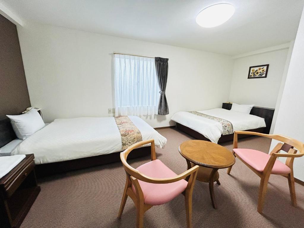 会津若松グリーンホテル会津的酒店客房带两张床和一张桌子以及椅子。