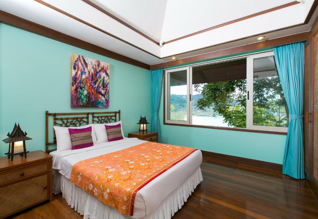 卡塔海滩Katamanda villa Sooksan的一间卧室配有一张蓝色墙壁的床和一扇窗户