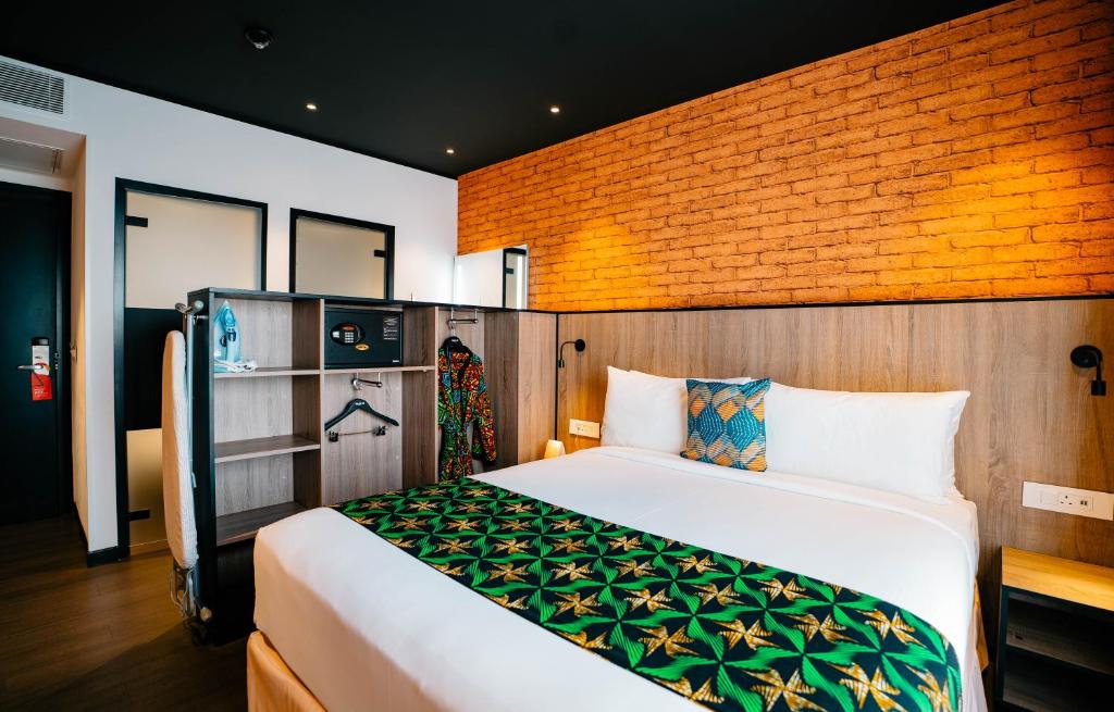 坎帕拉ONOMO Hotel Kampala的一间卧室设有一张床和砖墙