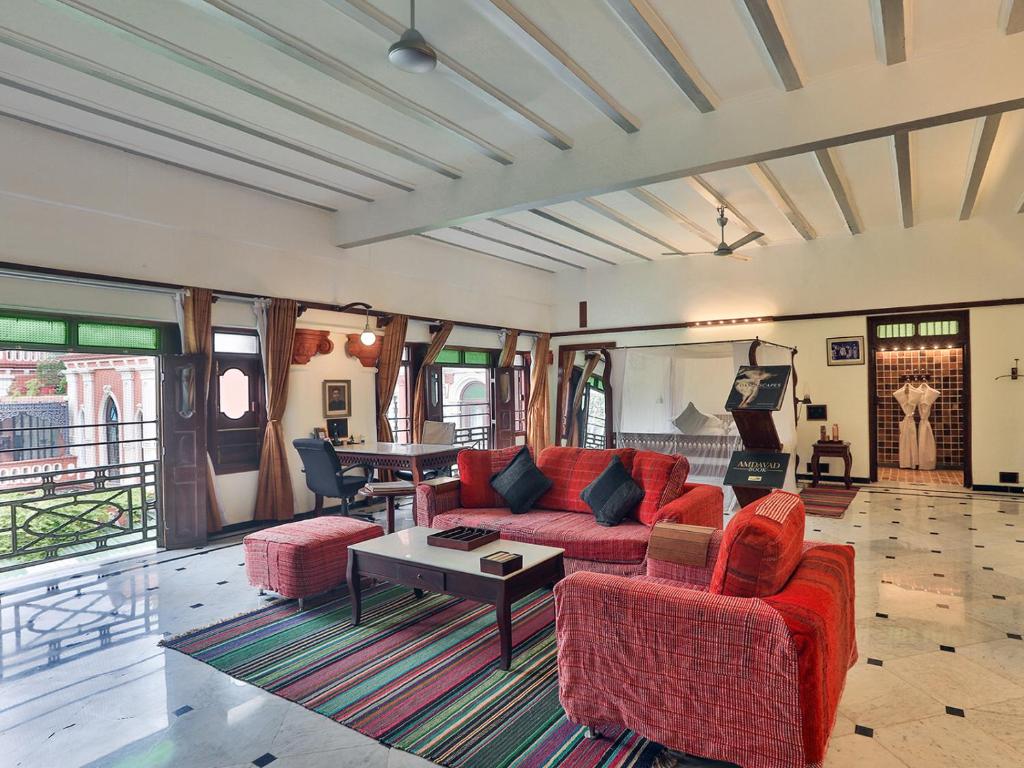 艾哈迈达巴德The House of MG-A Heritage Hotel, Ahmedabad的客厅配有红色的沙发和桌子