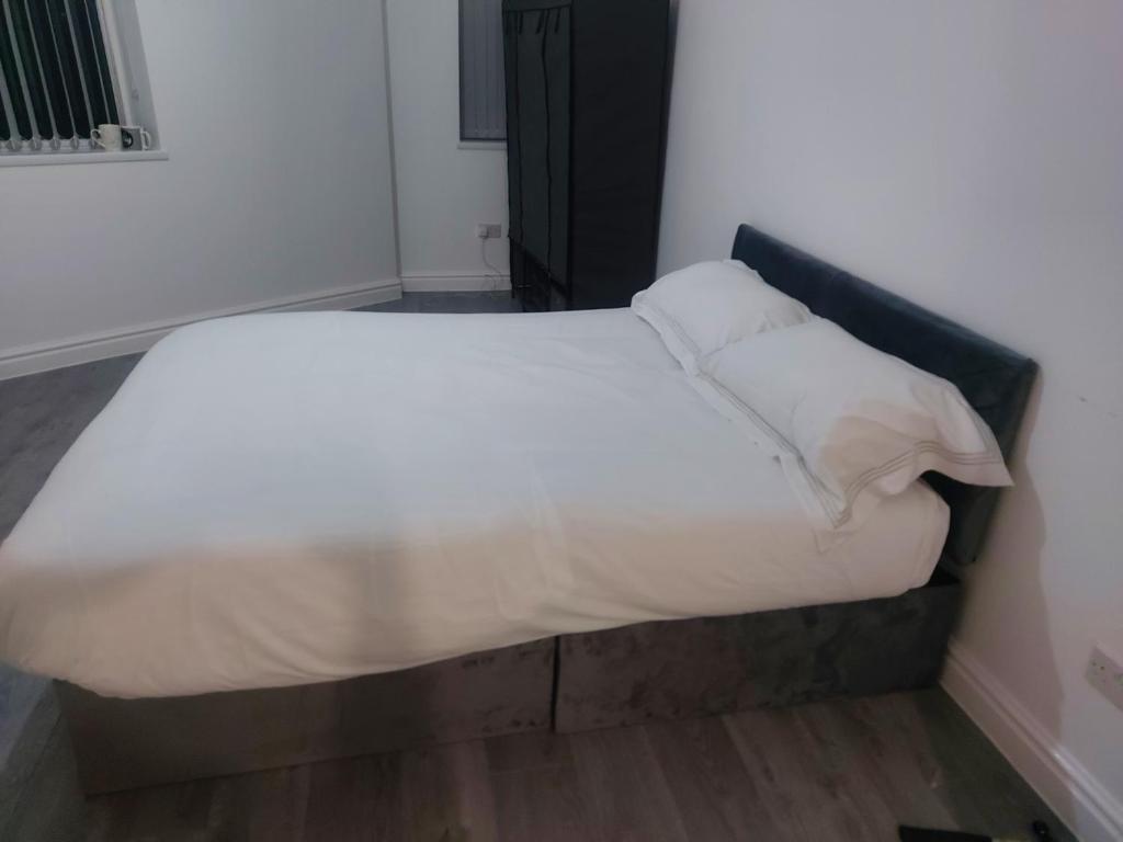 奥尔德姆Masfol comfort zone的一张带白色床单和枕头的床