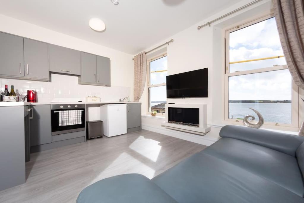科芙Unit 2 Island View Apartments With Stunning Harbour View的厨房配有白色橱柜和蓝色沙发