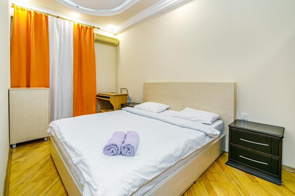 巴库Boulvard M Estate的一间卧室配有一张带紫色拖鞋的床