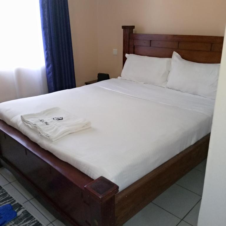 内罗毕New Carnation Pangani Hotel的床上坐着白色衬衫的床铺