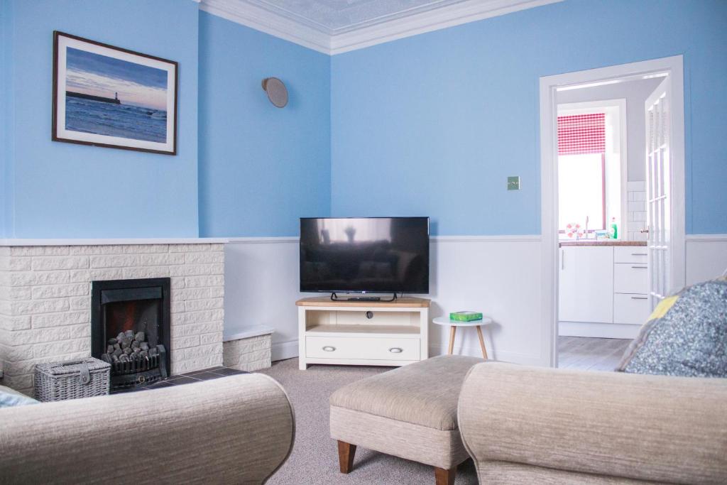 SpittalBeach House in Berwick Upon Tweed - 2 Double Bedrooms的蓝色的客厅配有电视和壁炉