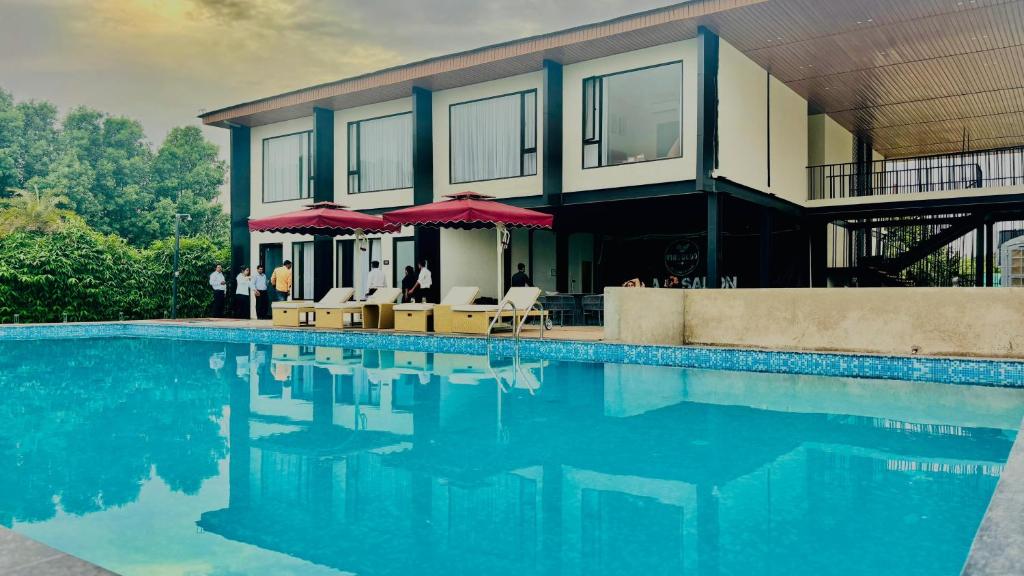 勒克瑙Vintclub Resort的一座房子,设有一座带椅子和遮阳伞的游泳池