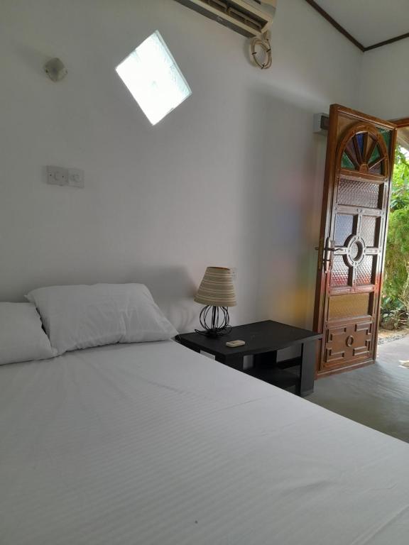 乌纳瓦图纳Aruna Villa的卧室配有白色的床和桌子