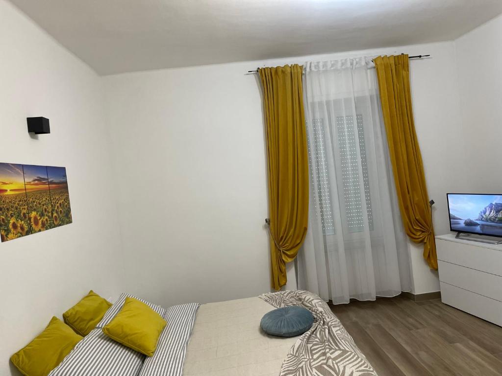 亚历山德里亚Savonarola Almarc 2的一间卧室配有一张黄色窗帘的床和一台电视