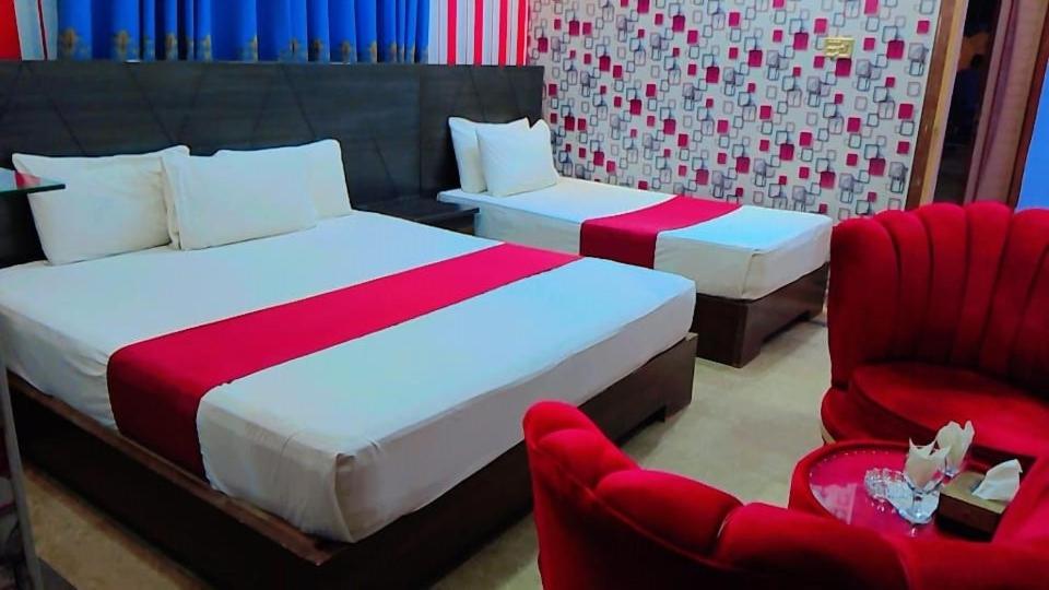 木尔坦Shelton One Hotel的一间卧室配有两张床和两张红色椅子