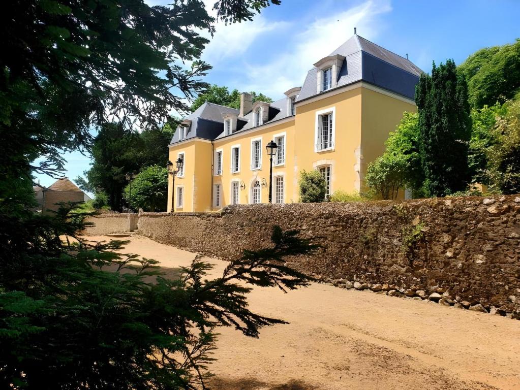 BonnevalHôtel du Château du Bois-Guibert的石头墙后面的黄色大房子