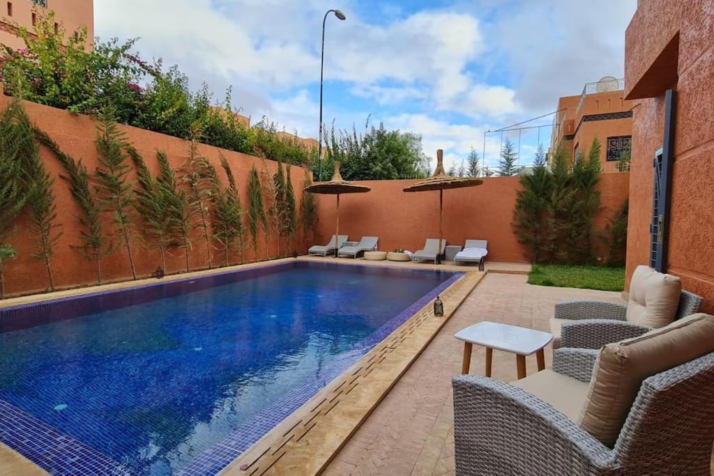 马拉喀什Belle Villa duplex avec piscine的后院的游泳池,配有椅子和桌子