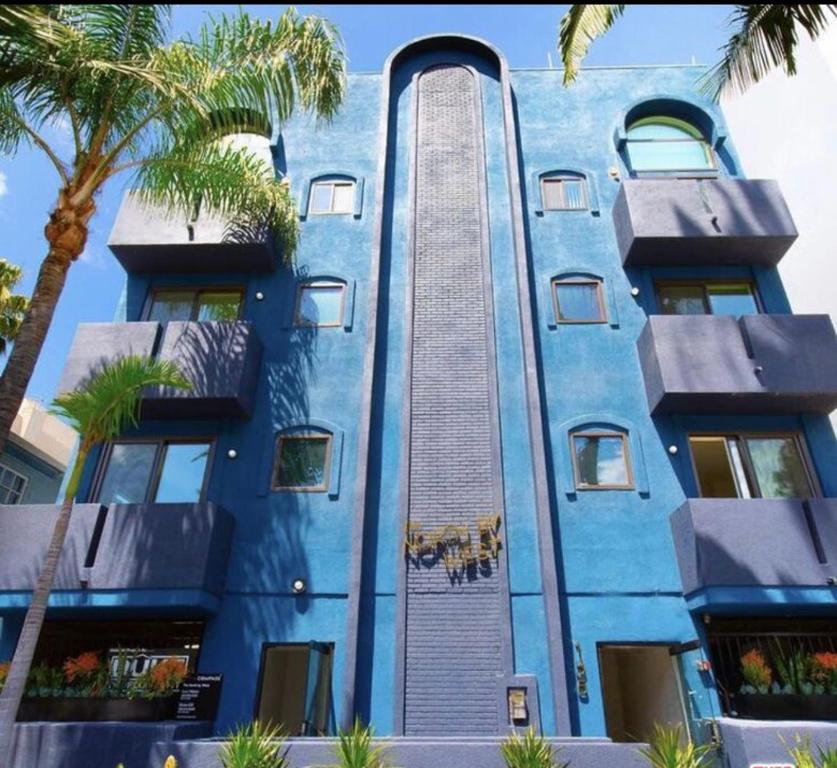 洛杉矶The Cloud II Los Angeles at Beverly Hills的一座蓝色的建筑,前面有棕榈树