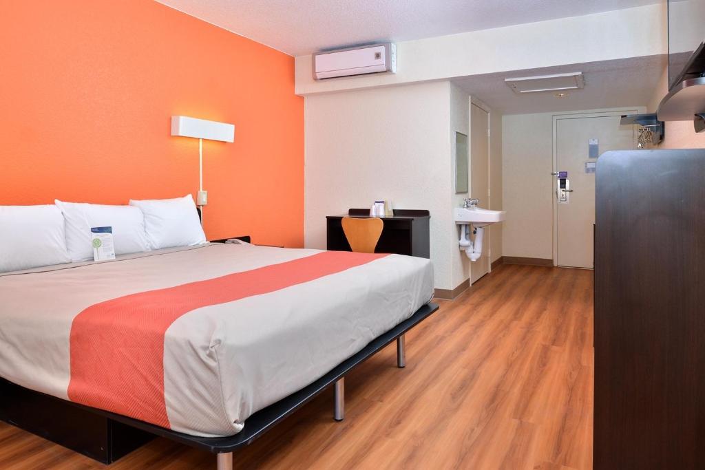 布劳利布劳利6号汽车旅馆的一间卧室配有一张带橙色墙壁的大床