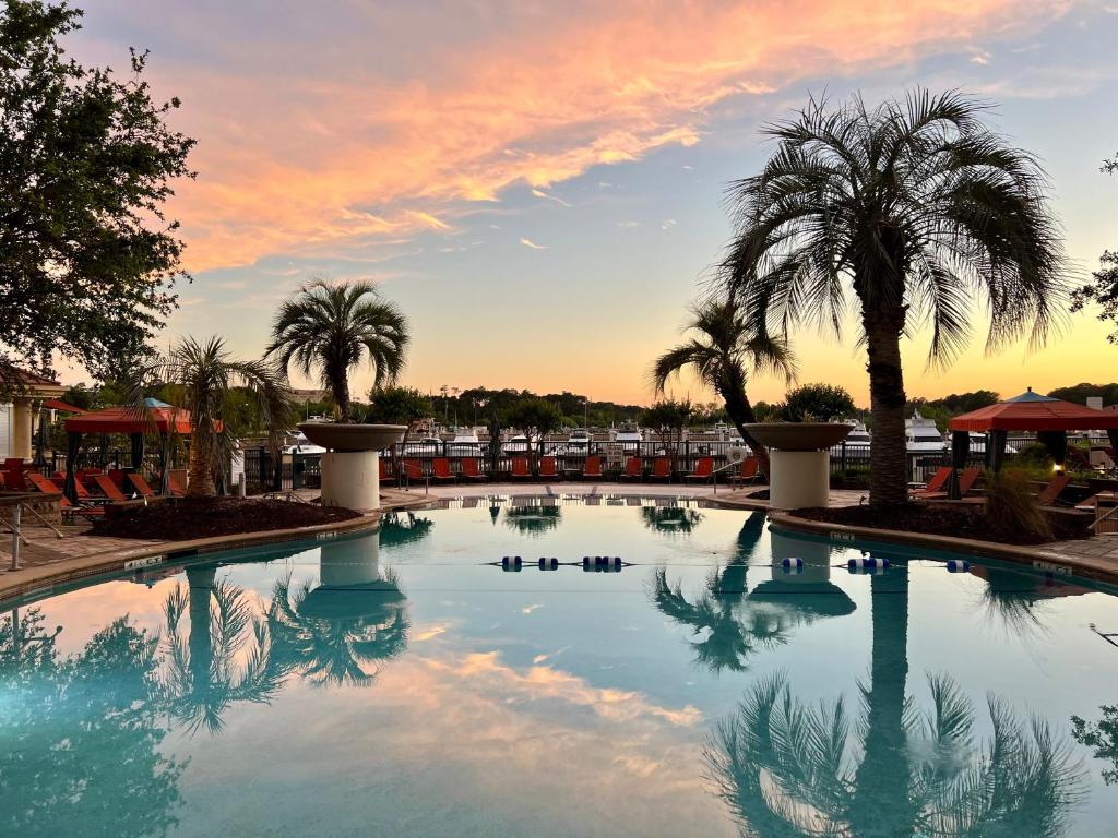 默特尔比奇格兰德杜内斯滨海酒店的一座棕榈树和日落的大型游泳池