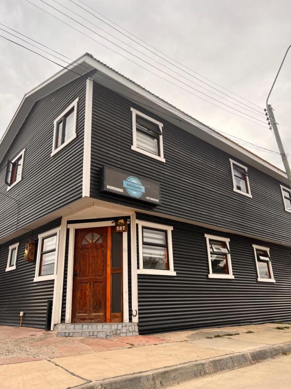 纳塔列斯港Hostal B&B Coastal Natales的一条黑色的建筑,街上有一扇棕色的门