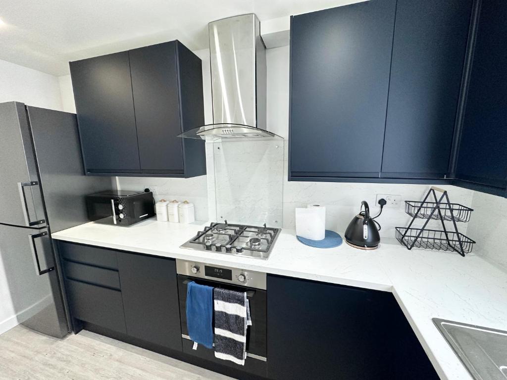 伦敦3 Bedroom Home In London - Lee - By Atleys Homes的厨房配有黑色橱柜和炉灶烤箱。