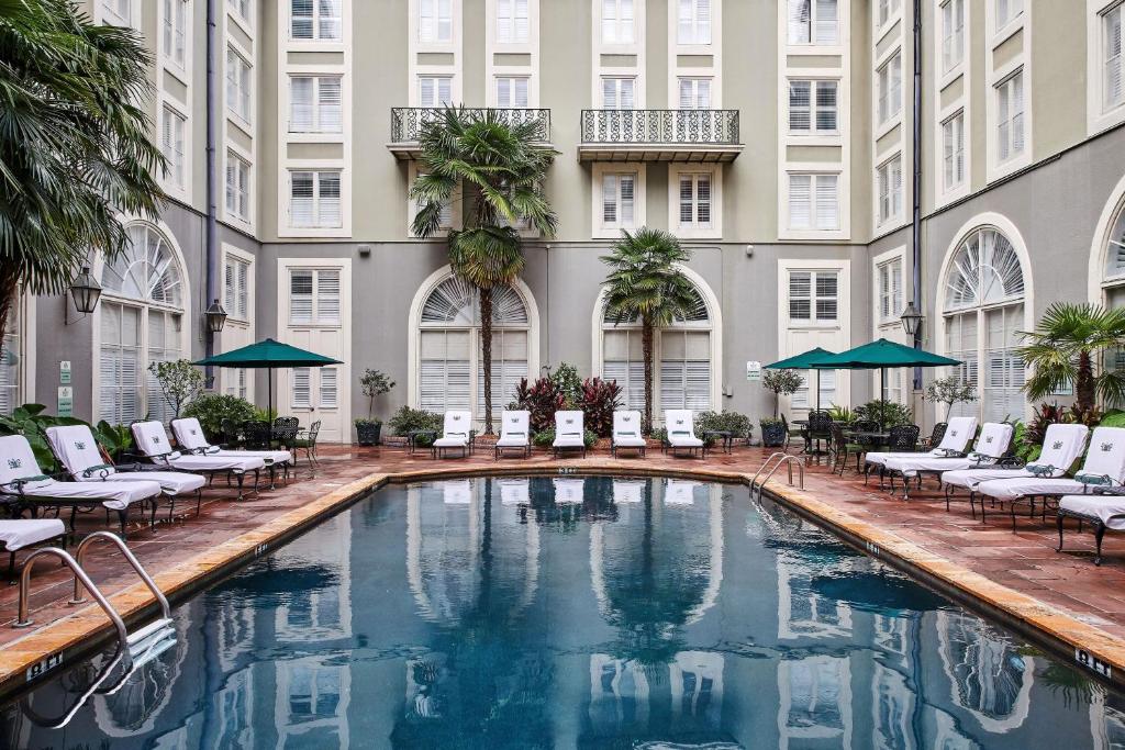新奥尔良波旁奥尔良酒店的游泳池位于酒店的庭院,配有椅子和遮阳伞