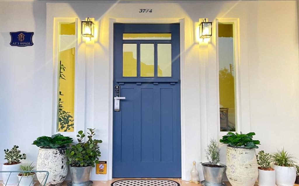 清迈Ay’s House的栽有盆栽植物的房子上的蓝色门
