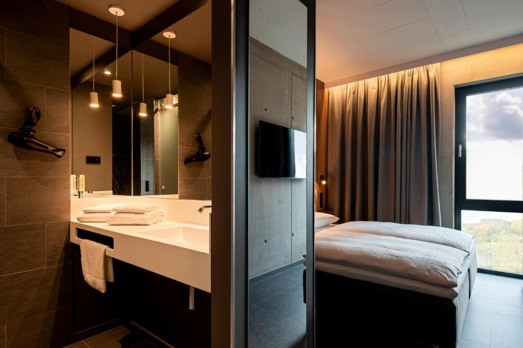 克洛滕Zleep Hotel Zürich-Kloten的一间带水槽、床和镜子的浴室