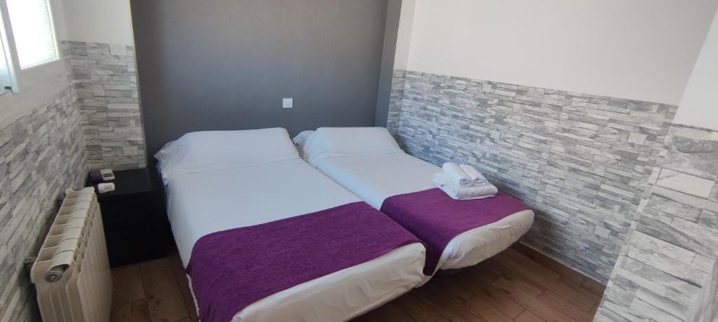 马亚达洪达埃斯科里亚尔旅馆的一间小卧室,配有两张床和砖墙