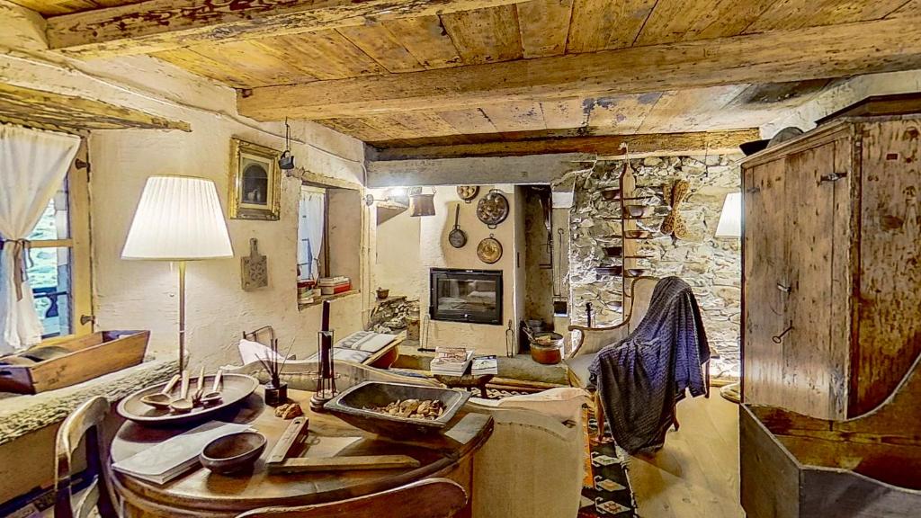 MolliaCa' Scocc, antica casa di montagna in Valsesia的客厅配有桌子和石墙