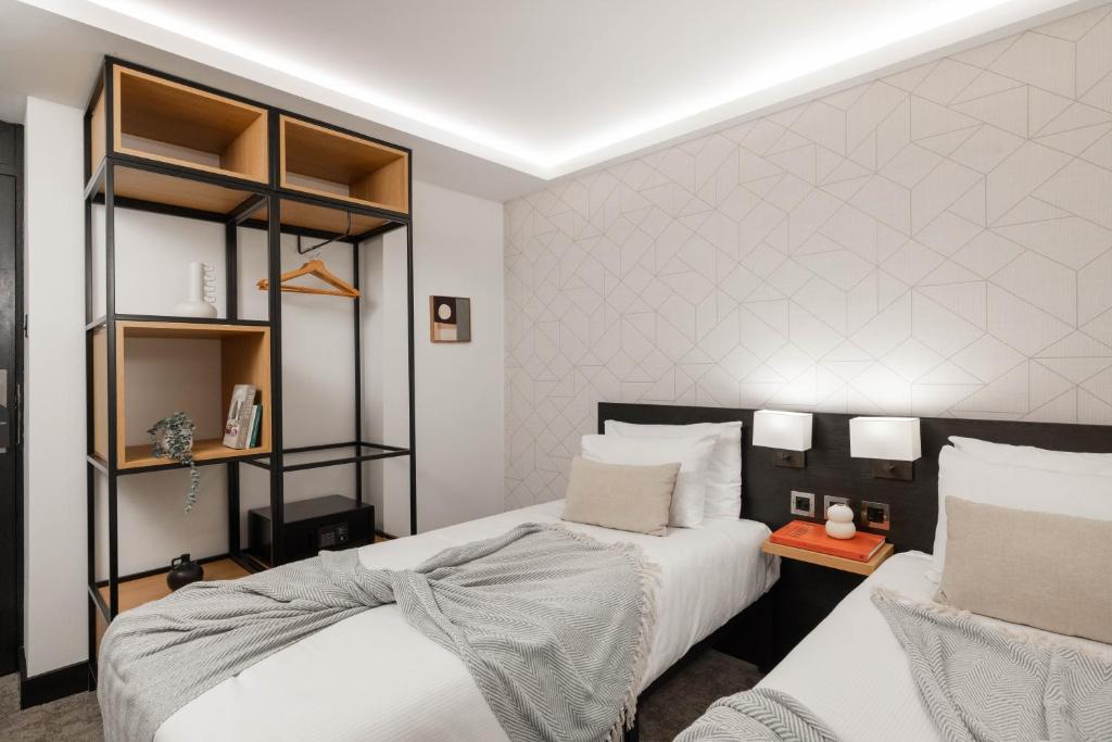 伦敦伦敦圣吉尔斯酒店的一间卧室设有两张床和书架