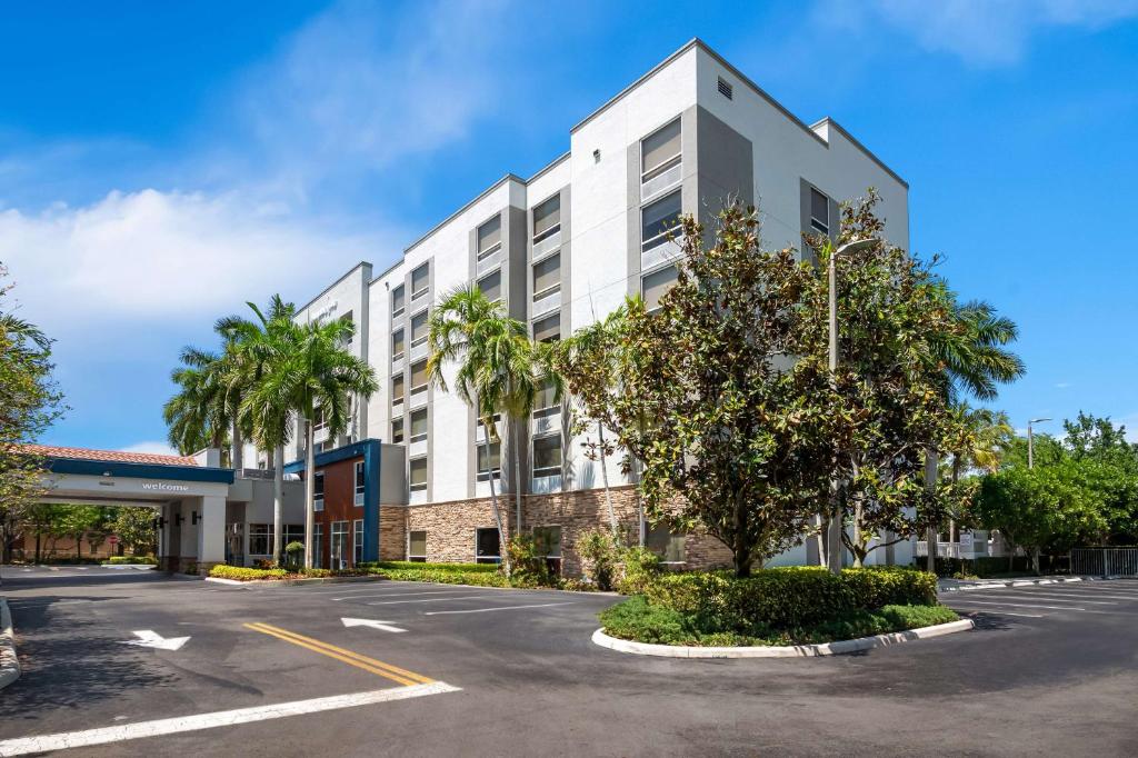 韦斯顿Hampton Inn Weston Fort Lauderdale的停车场内一座棕榈树成荫的白色建筑