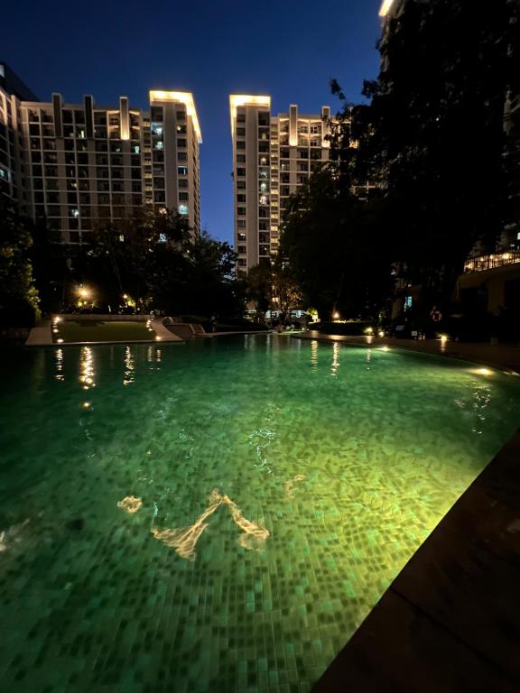 曼那Parkland Srinagarindra A的一座绿色的大泳池,其建筑背景是