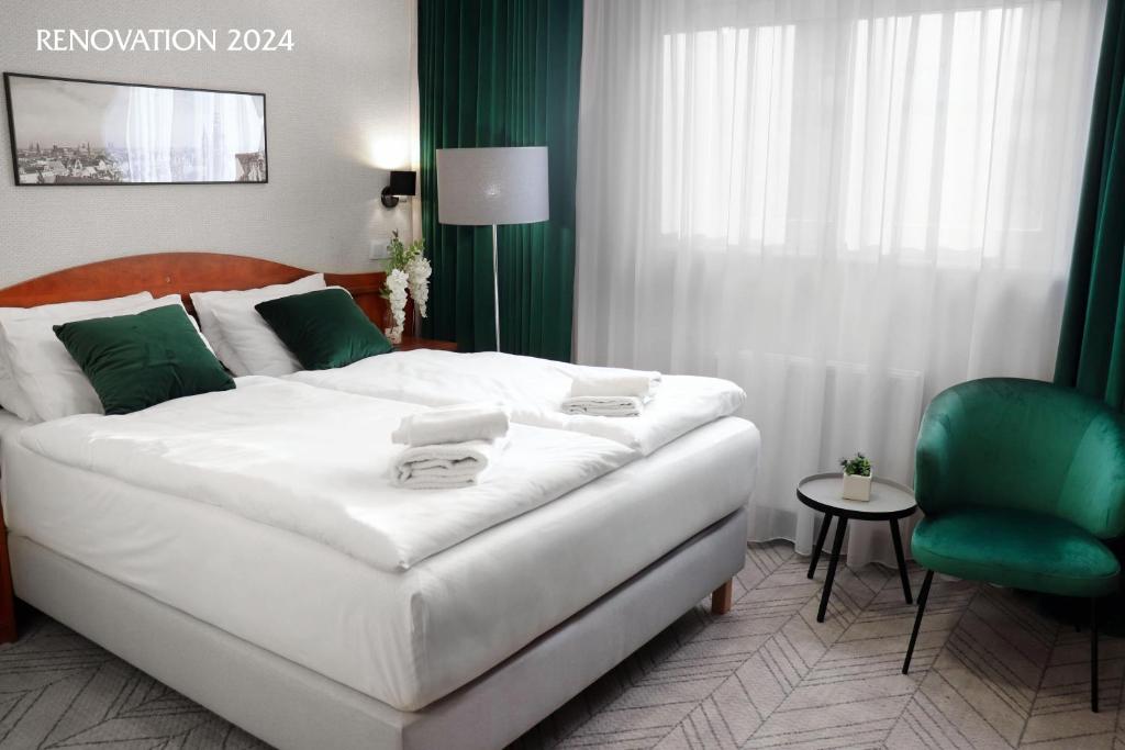 弗罗茨瓦夫波尼亚中枢酒店的卧室配有白色的床和绿色椅子