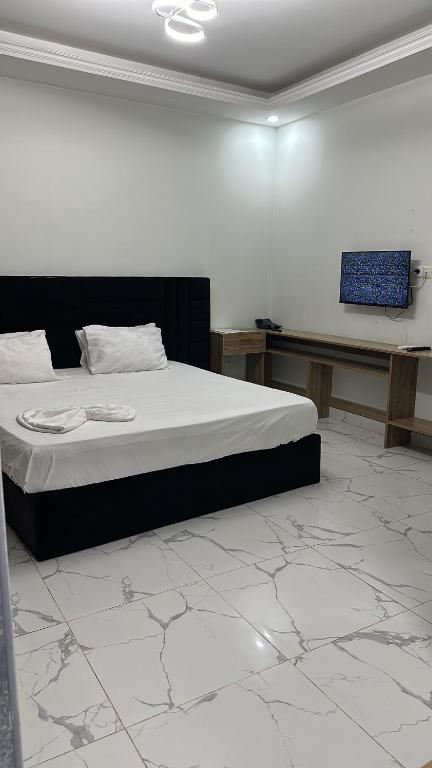 罗安达Convênio Residencial-Hotelaria & Turismo的一间卧室配有一张床,墙上配有电视