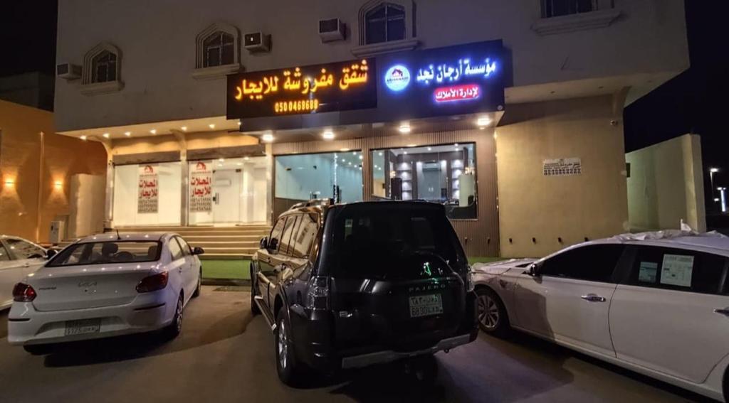 Al Nairyahشقق ارجان نجد المفروشه的两辆汽车停在大楼前的停车场