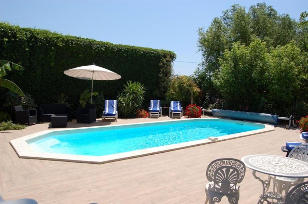 艾格-莫尔特Chambre BELEM - MAS SAINT LOUIS的庭院内的游泳池配有椅子和遮阳伞