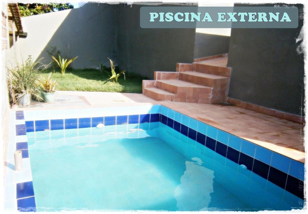 瓜拉派瑞HoStel de Setiba - HOSPEDARIA OCA RUCA的一座位于房子一侧的蓝色瓷砖游泳池