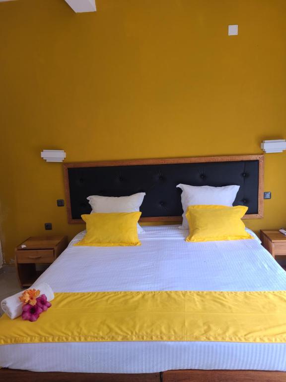 塔那那利佛Hotel Les Cygnes的一张大床,拥有黄色的墙壁和黄色的枕头