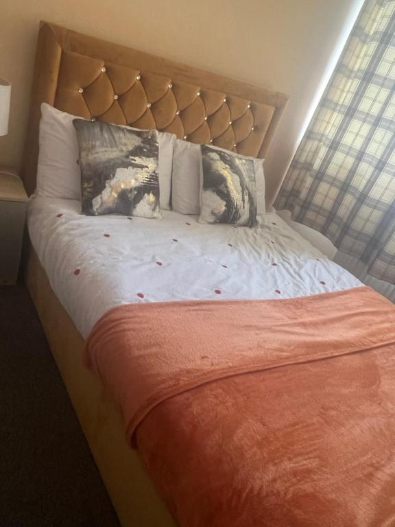 PitseaRoom in Essex的一张带橙色毯子和枕头的床