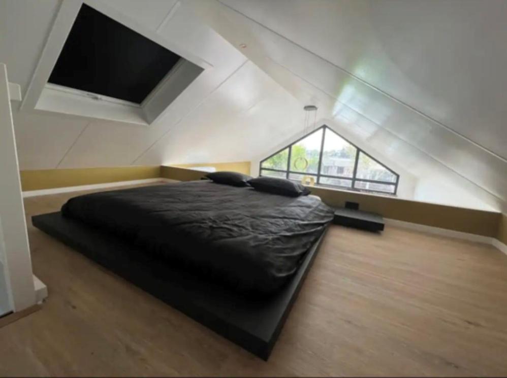 Velserbroek Cozy & Modern Tiny House的一间卧室配有一张黑色的床和一台平面电视。