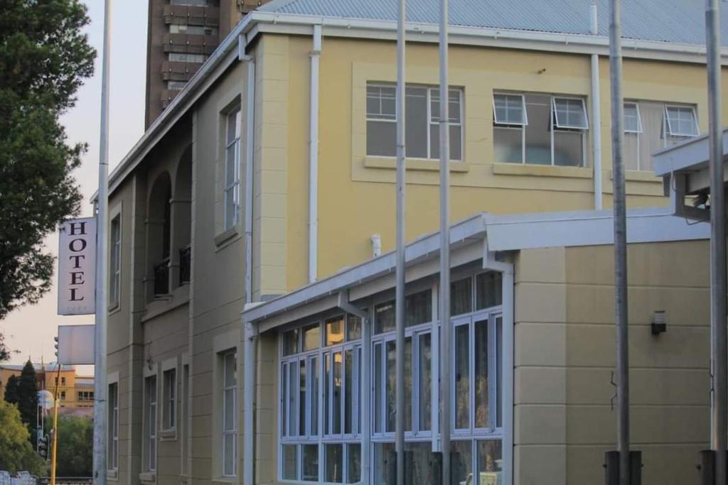 布隆方丹Sapphire Hotel Halevy Heritage的黄色的建筑,前面有标志