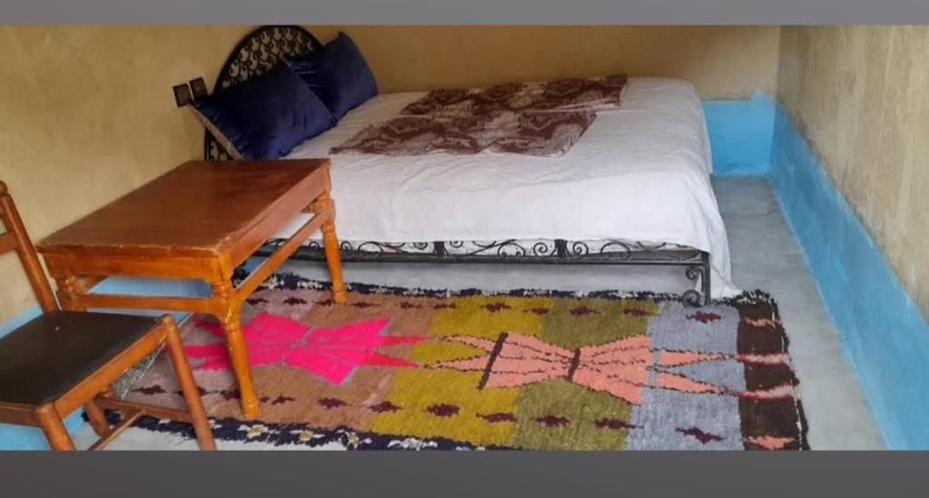 AmellagoAuberge amouger aouras的一间卧室配有一张带书桌和一张桌子的床。